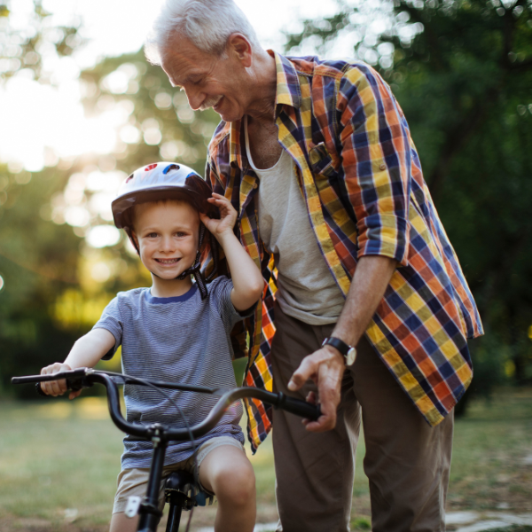 grandfather helping his grandson ride a bike