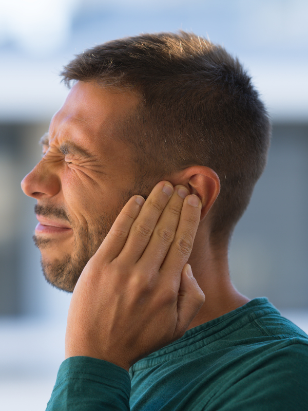 man holding his ear in pain