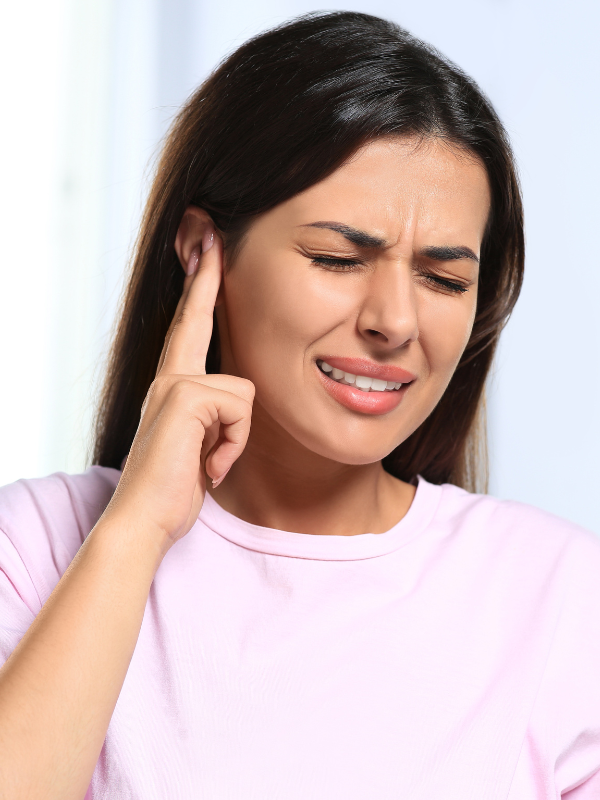 woman holding her ear in pain